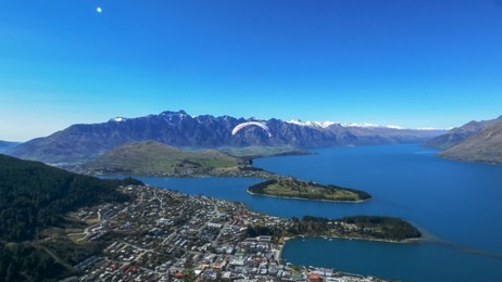 a paraglider takes off from skyline in queenstown, new zealand