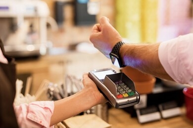 person paying at cafe with smart watch wirelessly on pos terminal