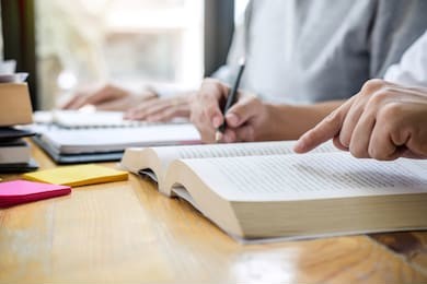 education, teaching, learning, technology and people concept. two high school students or classmates with helps friend do homeworks learning in classroom, tutor books with friends.