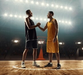 two professional basketball players shaking hands while standing on court before the game start