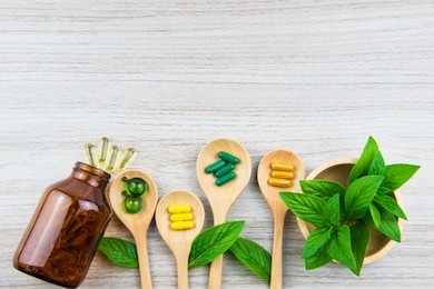 top view of antioxidants vitamin, pills, drug, capsule in wooden spoon, organic herbal medicine from nature green leaf supplemental and health care product on medical wooden background with copy space