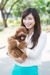 young girl holding dog on hands and looking at camera