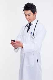 young asian doctor using smar phone isolated on white background.