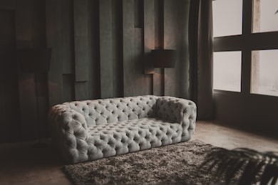 soft velvet grey sofa. minimalistic loft living room. textured gray wall. black floor lamp. gray rug near couch