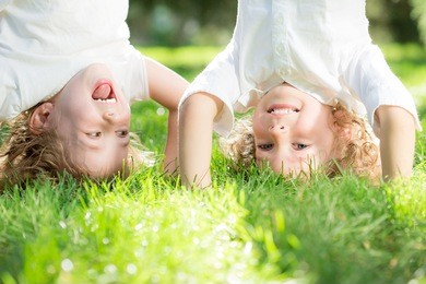 happy children standing upside down on green grass in spring park. healthy lifestyles concept.