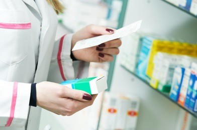 closeup hand of woman pharmacist with prescription and medicine at drugstore