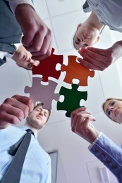 group of business people assembling jigsaw puzzle and represent team support and help concept