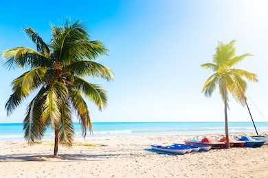 the tropical beach of varadero in cuba with sailboats and palm trees on a summer day sunset with turquoise water. vacation background.