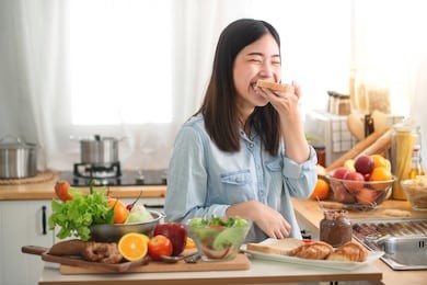 young asian woman in the kitchen prepare and eating sandwich for breakfast