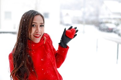young asian woman with long hair holding a red heart in her hand on winter time with snowflakes and copy space for texture. healthy people. valentine’s day,mother’s day concept