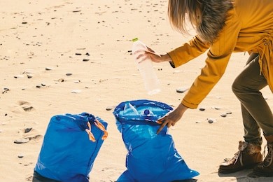 woman picking up plastic bottles on beach. environment and plastic. plastic free concept