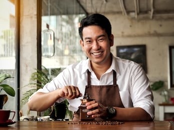 happy asian barista man grinding coffee beans on table, lifestle concept.