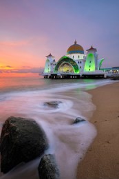 straits mosque of malacca, malaysia during sunset. the mosque is located on the reclaimed land at malacca island, malaysia