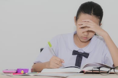 asian cute girl in school uniform doing homework and reading books on the table in the classroom
