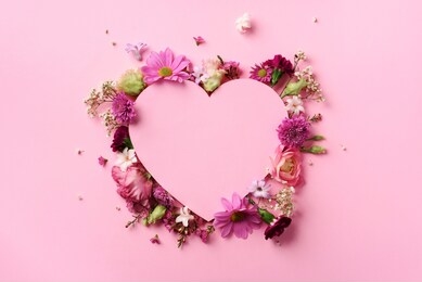 creative layout with pink flowers, paper heart over punchy pastel background. top view, flat lay. spring, summer or garden concept. present for woman day.
