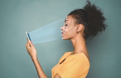 biometric identification. african-american woman scanning face with facial recognition system on smartphone
