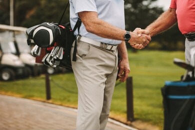 cropped shot of senior golf players shaking hands when meeting on a golf course. golfers greeting each other with a handshake before the game.
