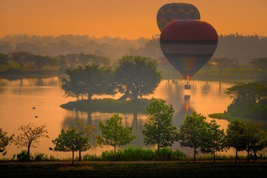 hot air balloons floating over lake at singha park chiangrai, thailand 