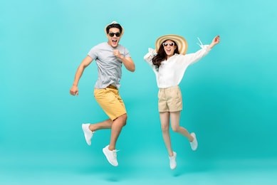 playful energetic asian couple in summer beach casual clothes jumping isolated on light blue background studio shot