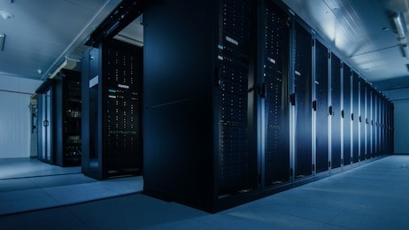 shot of a working data center with rows of rack servers. led lights blinking and computers are working.