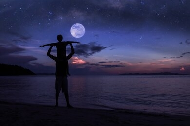 silhouette father and daughter on the beach with million stars galaxy ,the moon and blue sky early morning.