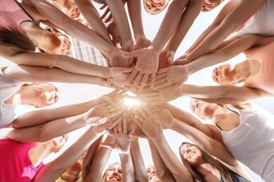 bottom view of women stacking hands before exercising in gym.