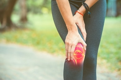 woman holding her knee with red pain on the skeleton