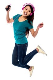pretty chinese girl enjoying music and jumping high in the air. full of joy.