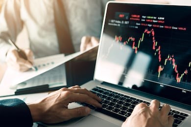 investors are using laptops entering investment websites stocks market and partners are taking notes and analyzing performance data.