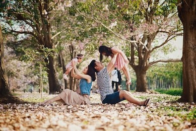 family activity. mother holding little baby and father holding big daughter raising them in the air with happiness in the park in spring season. happy family concept.