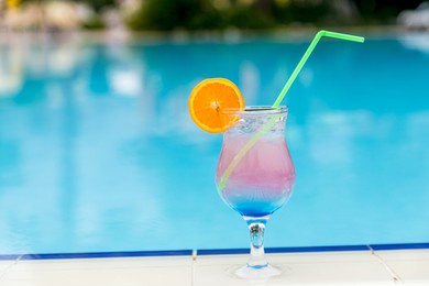 glass with cocktail on the edge of resort swimming pool. vacations concept.