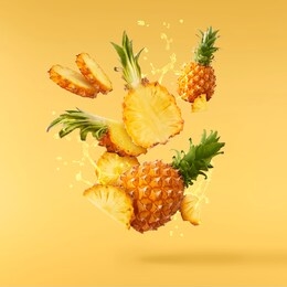 flying in air fresh ripe whole and cut baby pineapple with juice splash isolated on pastel yellow background. high resolution image