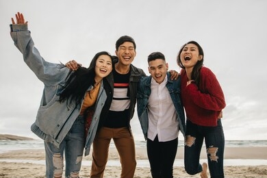 group of asian friends on the seashore. young people having great time together at the beach.