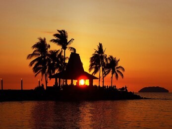 beautiful sunset view and silhouette coconut palm trees on beach in tanjung aru beach, kota kinabalu, sabah. malaysia, borneo.