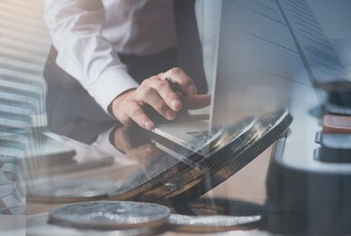 business financial investment and technology concept, double exposure of businessman, accountant working on laptop computer at office with coins, calculator and modern buildings office in the city