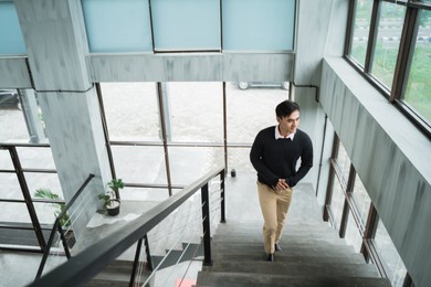 young asian businessman up the stairs enjoy situation in the office building