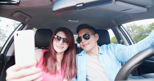 young couple use phone and take a selfie in the car