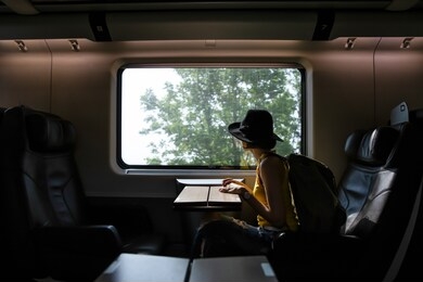 a beautiful hipster asian woman traveling on the train. sitting on the black leather cozy comfort seat in the business class of the train in europe. tourist travel concept.