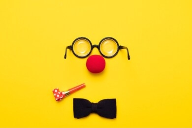 funny glasses, a red clown nose and tie on a colored background, like a face. flat lay. funny costume for the holidays. anonymous concept.