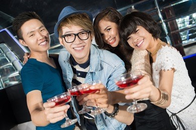 group of clubbing young people clinking glasses of cocktail