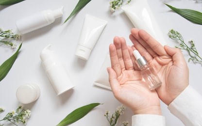 serum or essential oil w/ organic herbal extract. woman's hand holding vial w/ dropper and natural skincare bottles on white background. natural beauty cosmetic product. top view. copy space.
