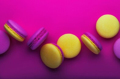 pink yellow macaroons on soft pink background table, place for text, minimalism style, violet purple neon color, top view