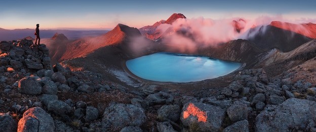 mountains and silhouette of standing man. early morning sunrise, landscape scenery of blue lake, wild mountains and huge volcano, autumn colors, tongariro national park new zealand north island