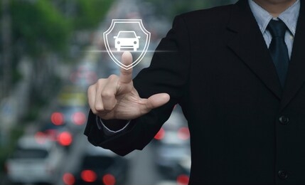 businessman pressing car with shield flat icon over blur of rush hour with cars and road in city, business automobile insurance concept