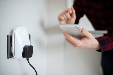man controlling smart plug using app on mobile phone