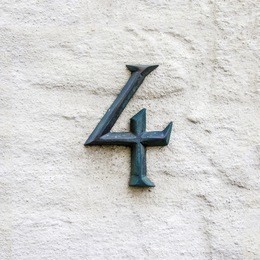 cast bronze house number four on a white plastered wall