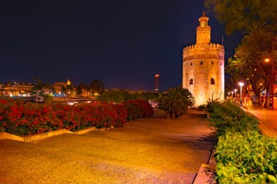 view of golden tower, torre del oro, of seville, andalusia, spain over river guadalquivir at sunset