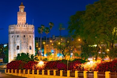 view of golden tower, torre del oro, of seville, andalusia, spain over river guadalquivir at sunset