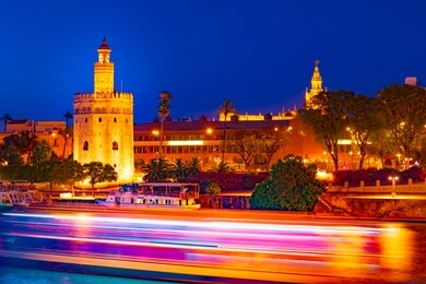 view of golden tower, torre del oro, of seville, andalusia, spain over river guadalquivir at sunset