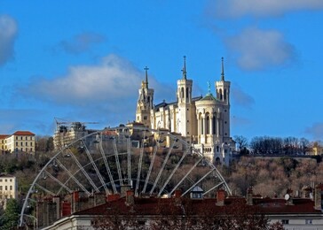 basilica of notre-dame de fourviere of virgin mary with ferris wheel, landmarks of lyon and fourviere hill with blue sky, france, europe